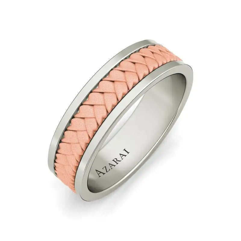 A silver ring with a pink braided leather inlay and the word "AZARAI" engraved on the inside.
