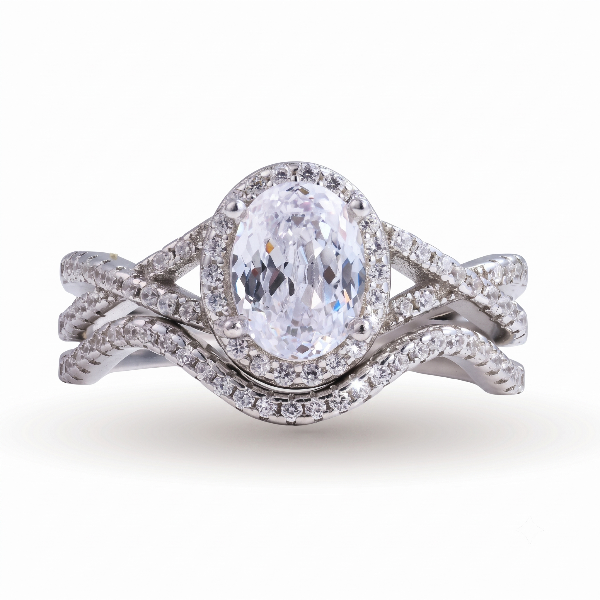 Introducing the Camille sterling silver bridal set: an oval-cut diamond ring with a halo setting and matching diamond-encrusted bands, crafted in sterling silver and elegantly displayed on a white background.