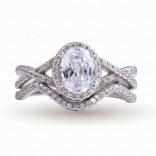Introducing the Camille sterling silver bridal set: an oval-cut diamond ring with a halo setting and matching diamond-encrusted bands, crafted in sterling silver and elegantly displayed on a white background.