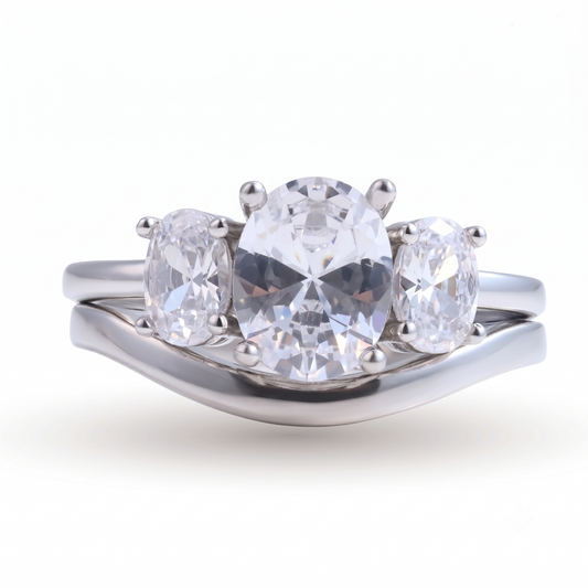 The Everly sterling silver engagement set features a three-stone oval diamond engagement ring with a curved matching band, both crafted in radiant sterling silver and elegantly displayed on a white background.