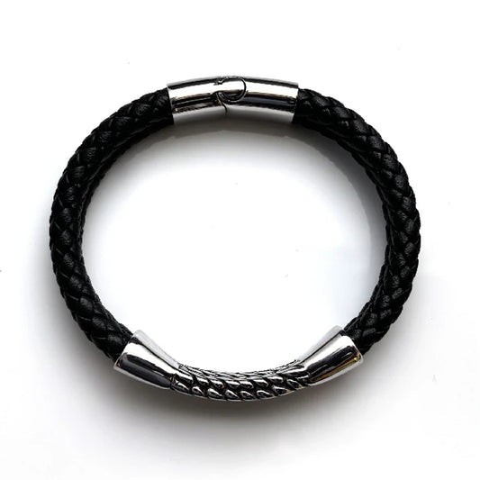 The Harvest Braided Leather Men's Bracelet features black braided leather, a stainless steel centerpiece, silver metal clasp, and decorative silver detailing, displayed on a white background.