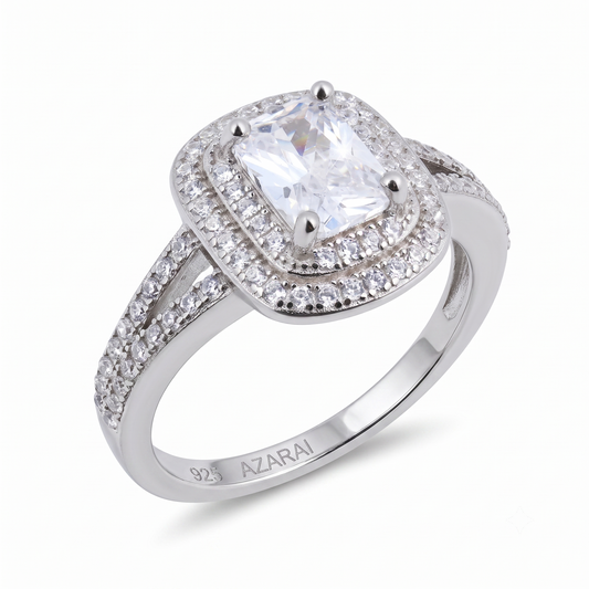 Celebrate your love story with the Lina sterling silver engagement ring, featuring a cushion-cut center stone surrounded by a dazzling double halo of smaller gems. The split shank band sparkles with additional accents and is stamped "925 AZARAI" on the inside, ensuring genuine style and craftsmanship.