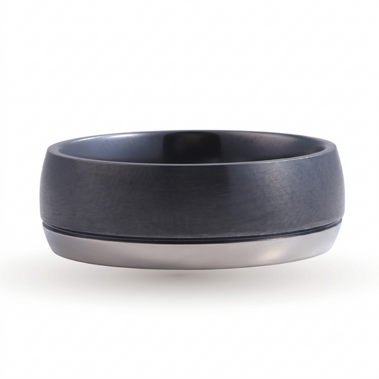 Introducing the Oakland black titanium wedding band—a modern and sophisticated ring featuring a striking two-tone design. This ring displays a wide black brushed finish band on top, complemented by a thinner silver band beneath. Crafted for lasting durability and distinct style, the Oakland black titanium wedding band is shown against a white background, making it the perfect choice for those seeking an elegant and memorable wedding band.