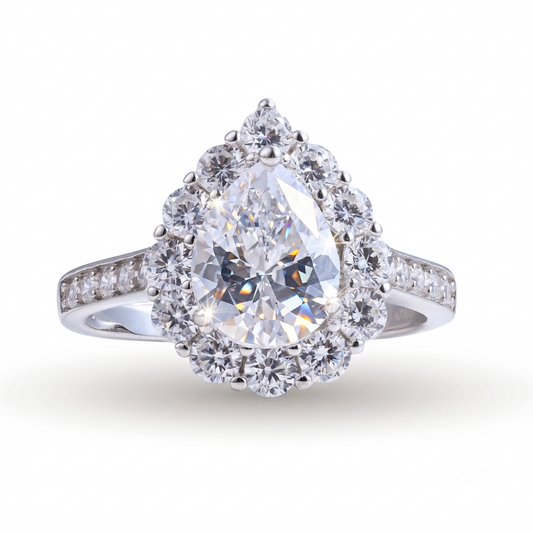 The Oriana sterling silver engagement ring showcases a pear-shaped diamond encircled by a halo of round diamonds, with a band adorned with delicate accent stones—all expertly crafted in radiant sterling silver. This stunning ring blends timeless elegance with contemporary style.
