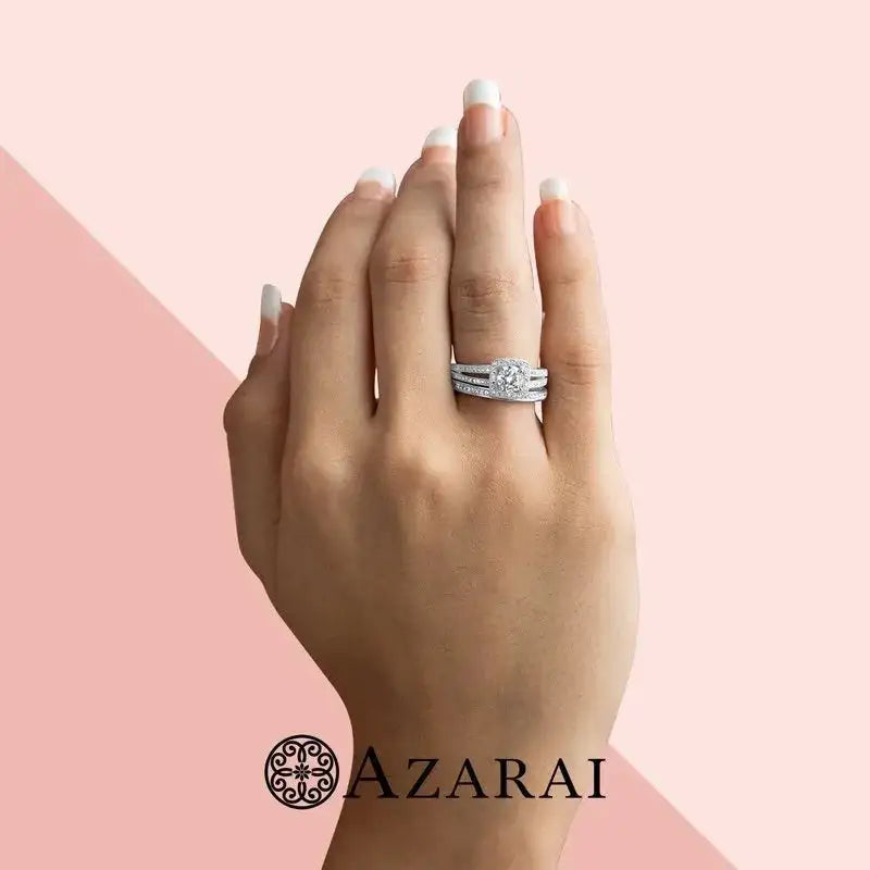 A hand with a French manicure wears the elegant Eva sterling silver bridal set on the ring finger, displayed above the Azarai logo on a pink and beige background.