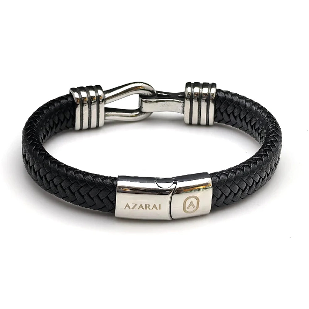 The Stirrup Braided Leather Men's Bracelet features black braided leather, a stainless steel clasp engraved with "AZARAI," and silver accents—creating a sleek design inspired by classic equestrian jewelry.