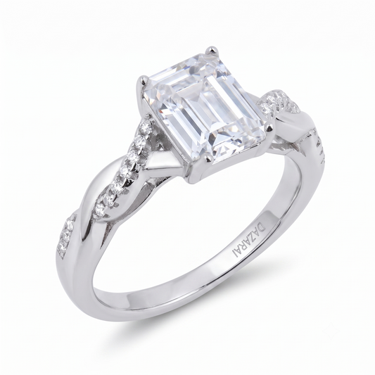 A sterling silver Sia Emerald engagement ring featuring an emerald-cut center stone with smaller diamonds set along the twisted band, perfect for an elegant proposal.