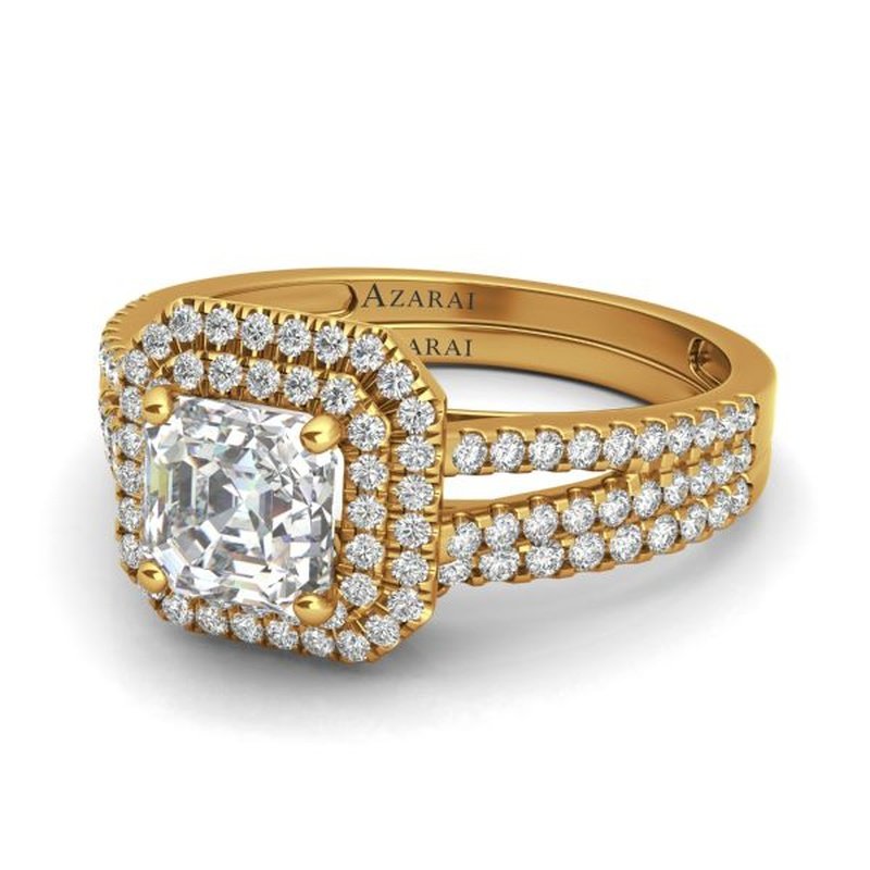 Beatrix 9kt gold bridal set with a cushion-cut central diamond surrounded by a double halo of smaller diamonds and a diamond-set band.
